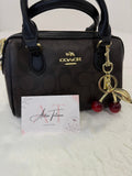 Bolso Mini Coach Rowan marrón con charm de cerezas