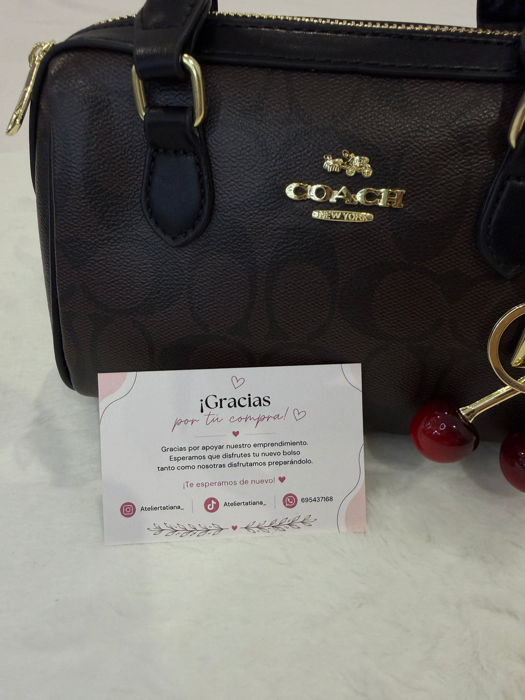 Bolso Mini Coach Rowan marrón con charm de cerezas